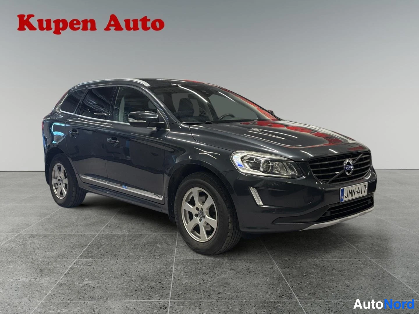 Etuviisto, nokka oikealle: Tummanharmaa Volvo XC60 kulmaetukuva sisätiloissa, rekisteritunnus.