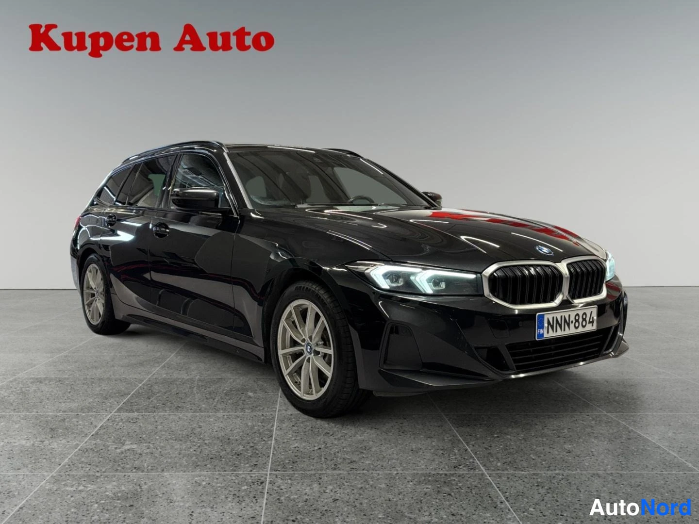 Etuviisto, nokka oikealle: Musta BMW 3-sarjan farmari kolmivartalokuva edestä oikealta, rekisterillä.