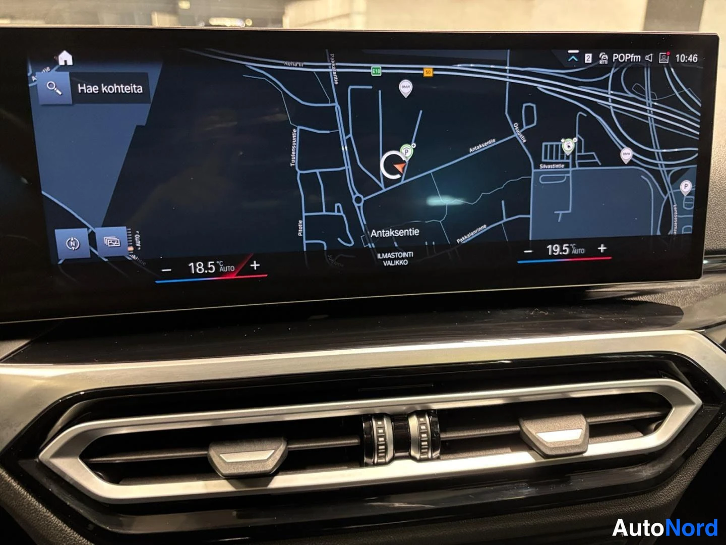 Ohjaamo: Kojelaudan infotainment-näyttö, jolla näkyy kartta navigaatiosta ja kaksivaiheinen ilmastointiasetus (18,5 °C ja 19,5 °C Auto).