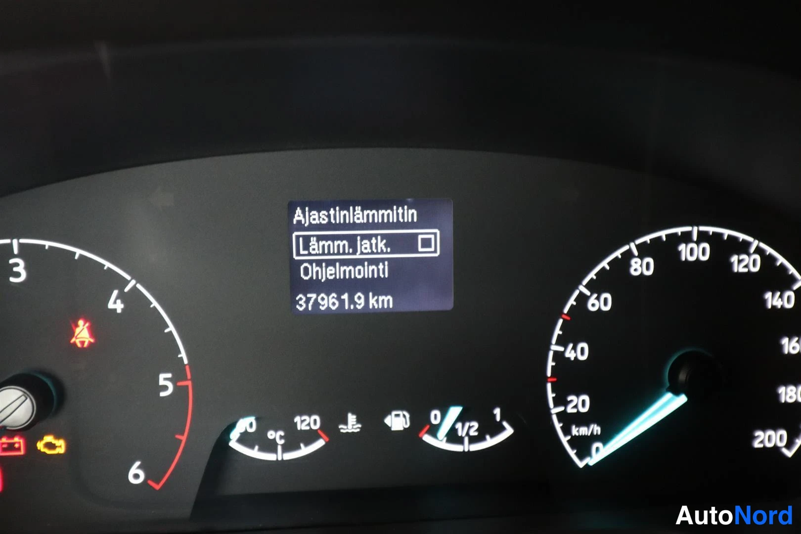 Yksityiskohta: Mittariston näyttö, jossa ajastinlämmittimen valikko (Lämm. jatk. ja Ohjelmointi) sekä km-arvo 37961.9.