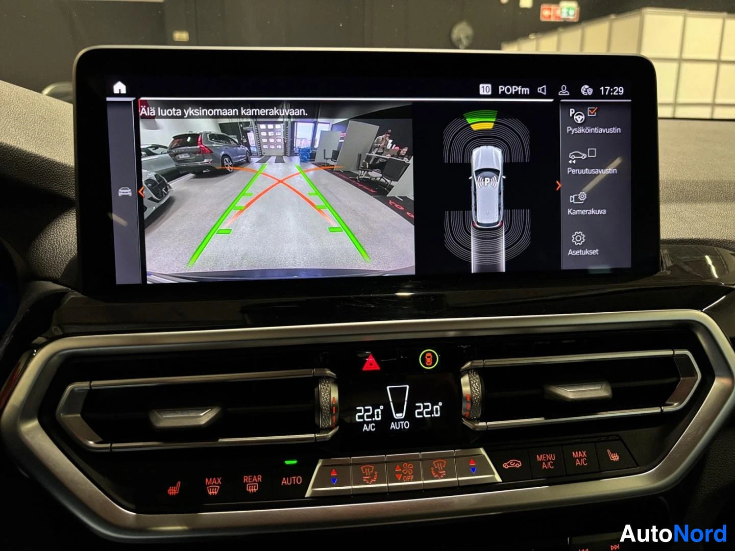 Ohjaamo: Keskuskonsolin infotainment-näyttö näyttää peruutuskameran kuvan ja pysäköintitutkan, alla ilmastoinnin A/C AUTO -asetukset 22,0°.