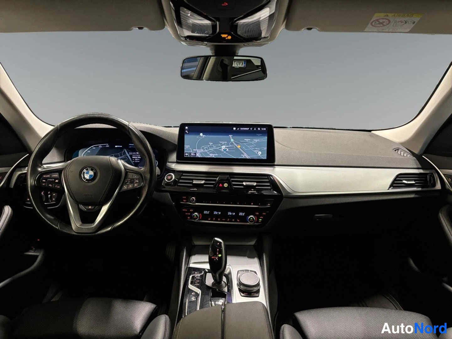 Ohjaamo: Ohjaamo kuvattuna takaistuimelta: BMW-ohjauspyörä, digitaalinen mittaristo, kartta näytöllä ja keskikonsoli.