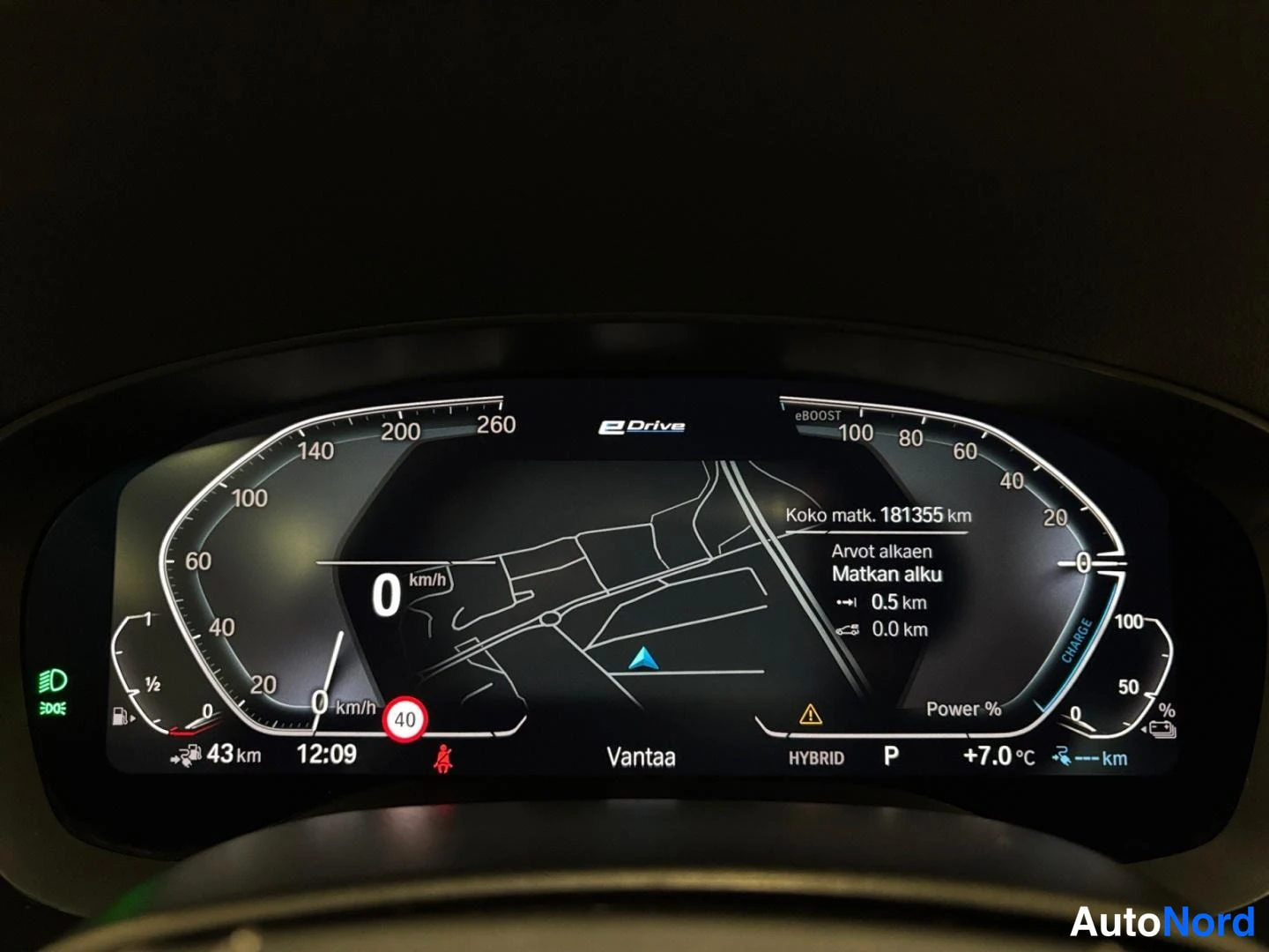 Yksityiskohta: Mittariston näyttö, jossa kokonaismatka 181355 km, HYBRID-tila ja eDrive-merkintä.