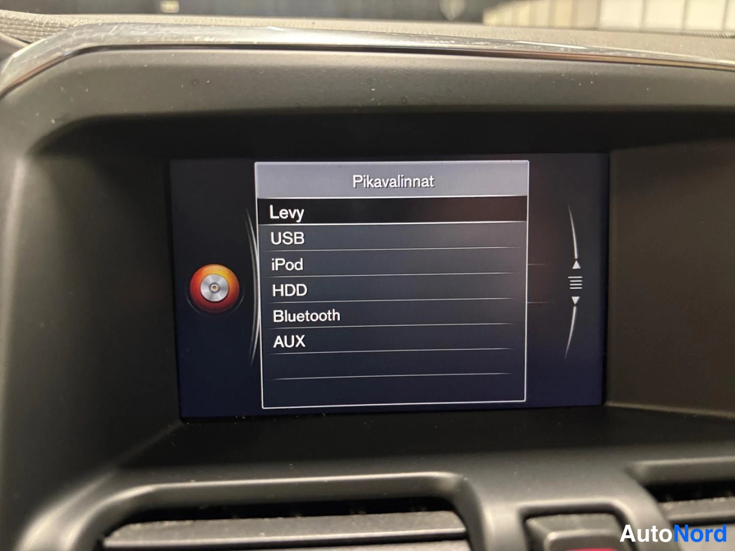 Yksityiskohta: Infotainmen näyttö, jossa Pikavalinnat-valikko: Levy, USB, iPod, HDD, Bluetooth, AUX
