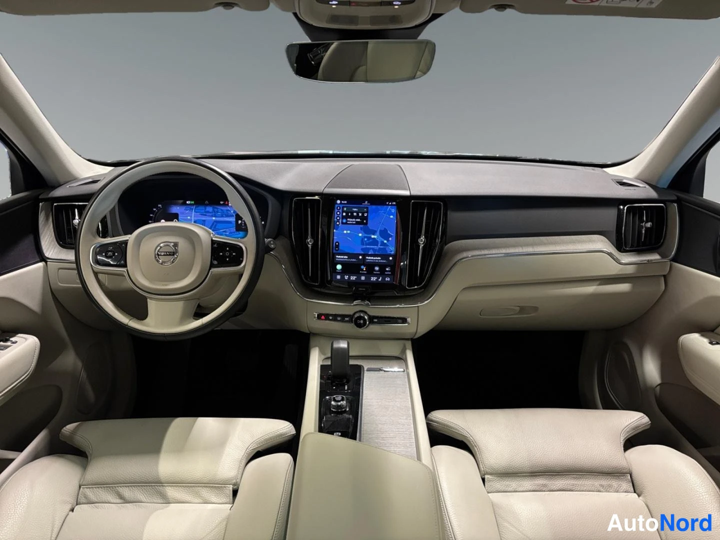 Ohjaamo: Kojelauta näytöllä navigointikartalla, Volvo-ohjauspyörä ja beizee nahkapenkit.