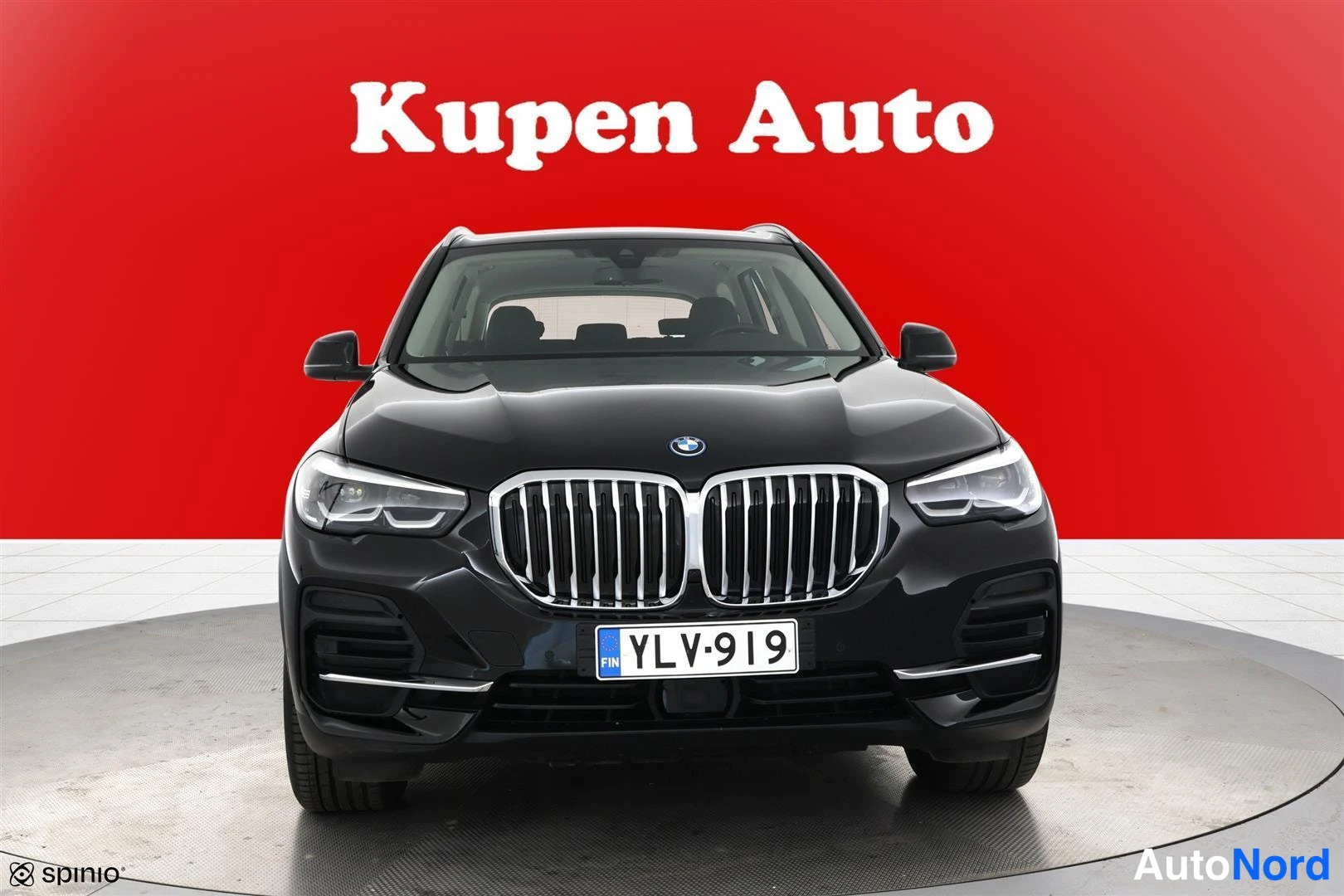 Edestä: BMW X5 suoraan edestä, keulagrilli ja -rekisterikilpi, punainen tausta.