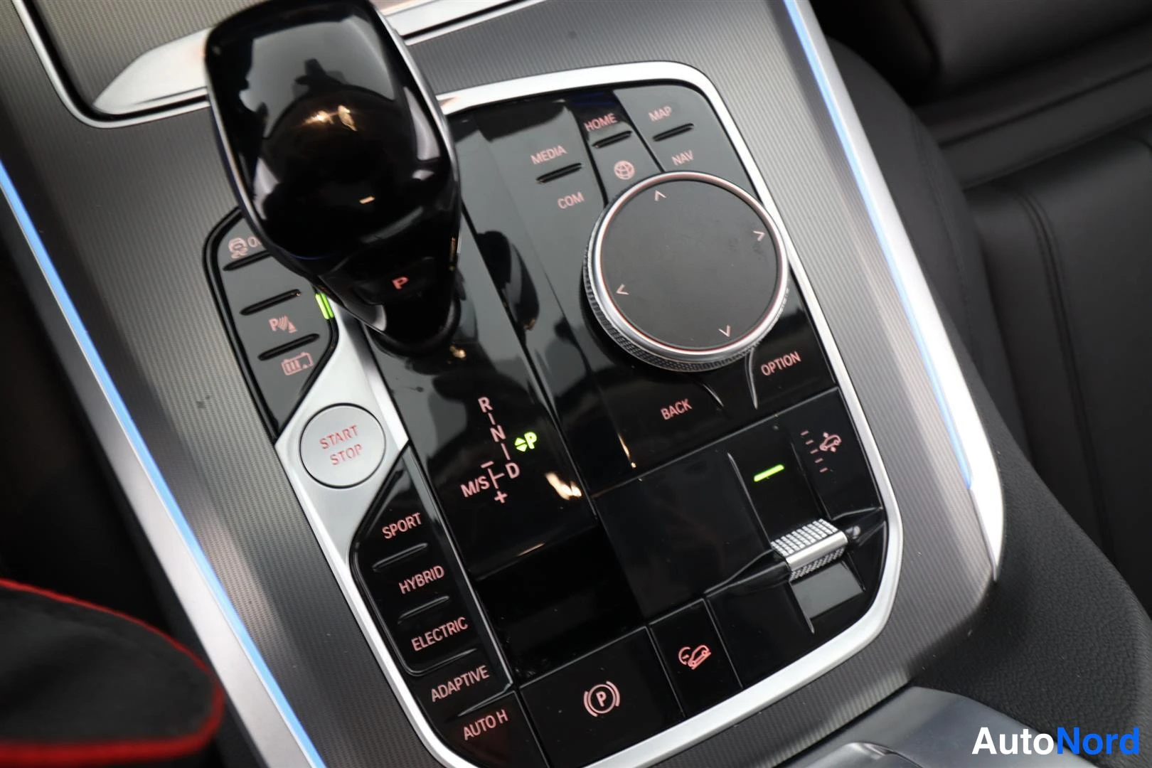 Yksityiskohta: Auton keskitunnistin: vaihteenvalitsin, iDrive-ohjain, käynnistyspainike ja ajotilak Fortress -painikkeet (Sport, Hybrid, Electric, Adaptive).