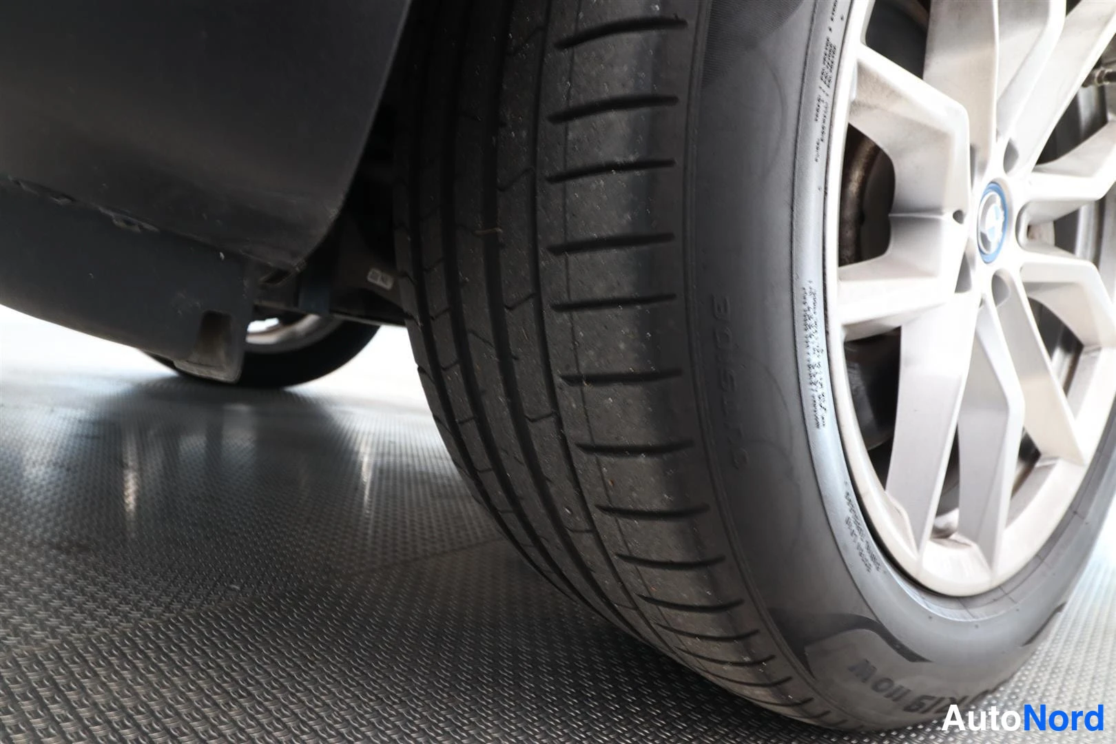 Yksityiskohta: Lähikuva auton renkaasta ja hopeisesta vanerelta; Michelin-rengas, kyljessä teksti PILOT SPORT.