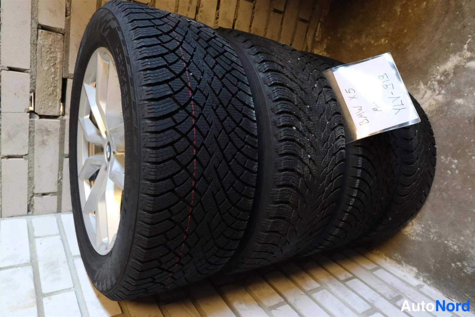 Muu: Pinossa neljä talvirengasta vanneilla; lapussa käsin kirjoitettu 'BMW X5 '.