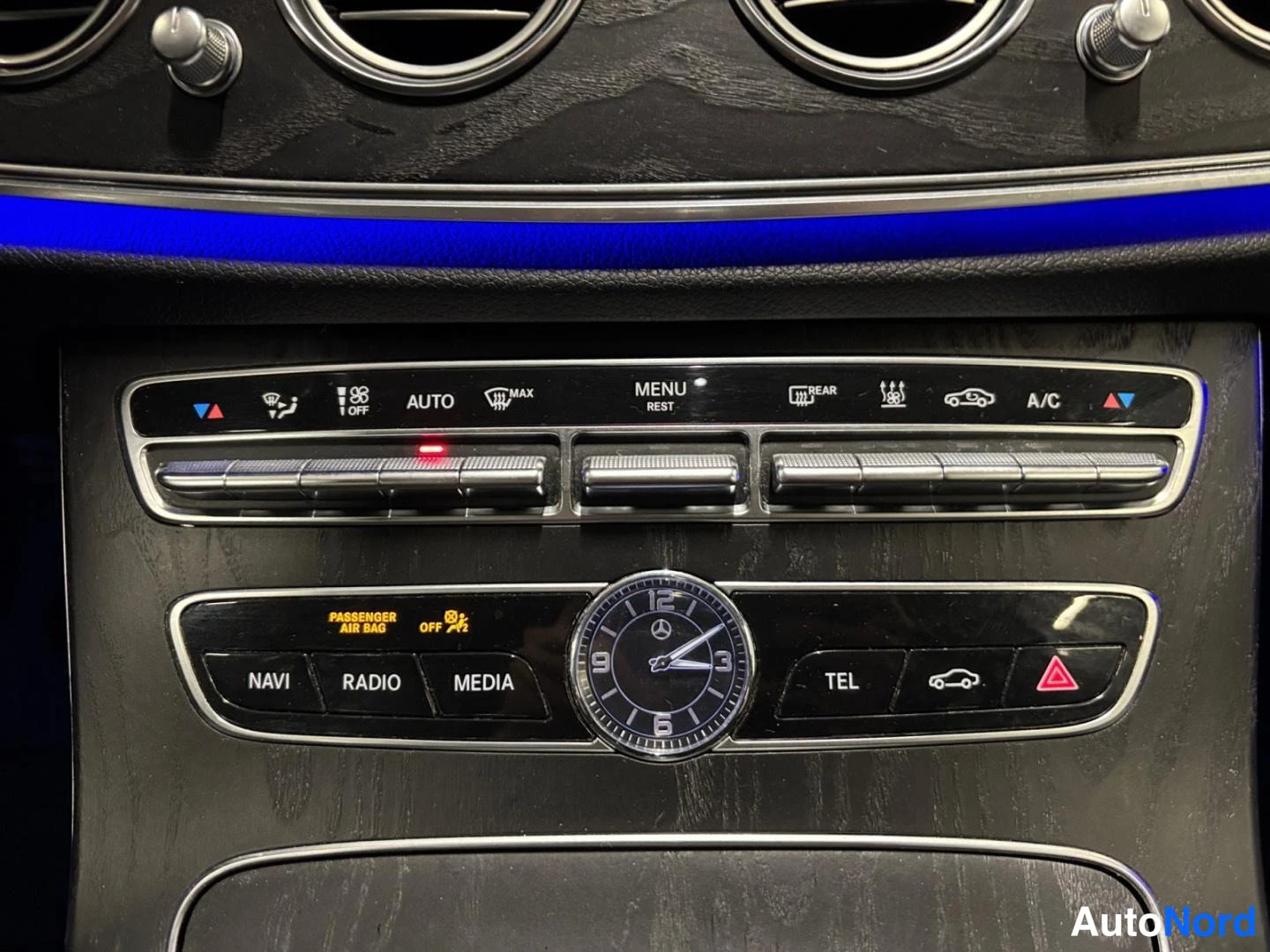 Yksityiskohta: Keskikonsolin paneeli: ilmastointi (AUTO, A/C), NAVI-, RADIO-, MEDIA- ja TEL-napit sekä kello