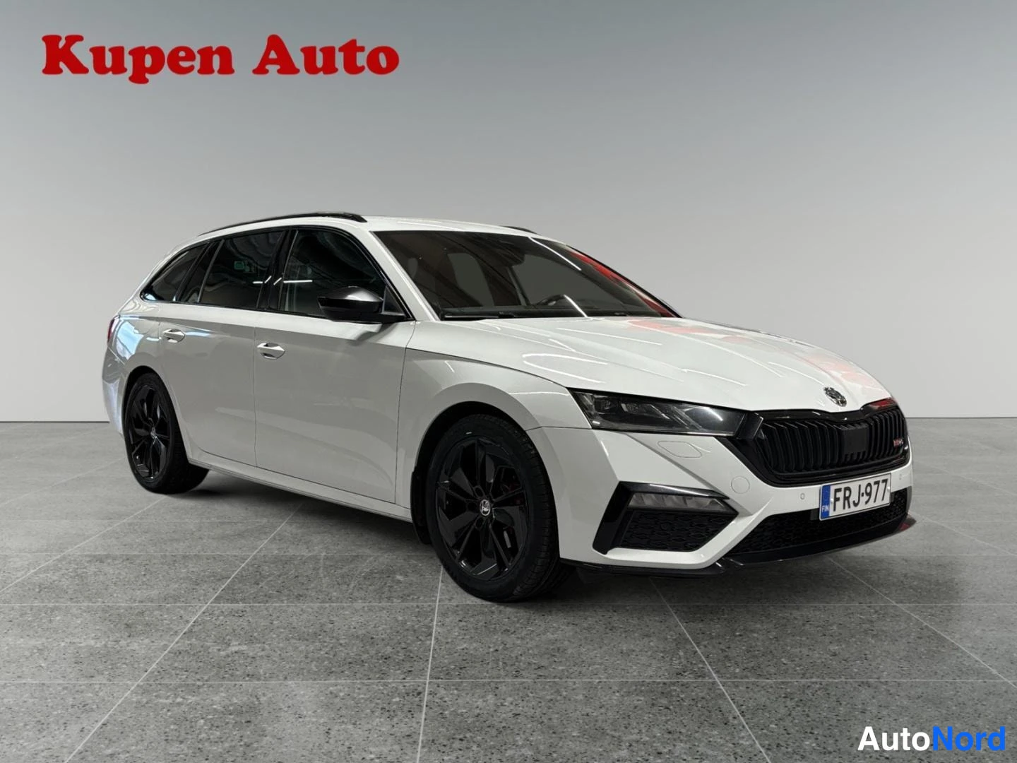 Etuviisto, nokka oikealle: Valkoinen Skoda Octavia Combi RS kulmasta edestä oikealta kuvattuna, mustat vanteet.
