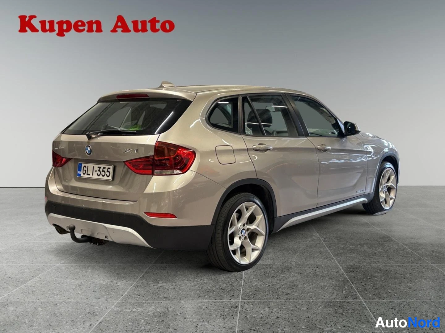 Takaviisto: BMW X1 taka­viistosta oikealta, 'X1'-merkintä takaluukussa, vetokoukku takapuskurissa.