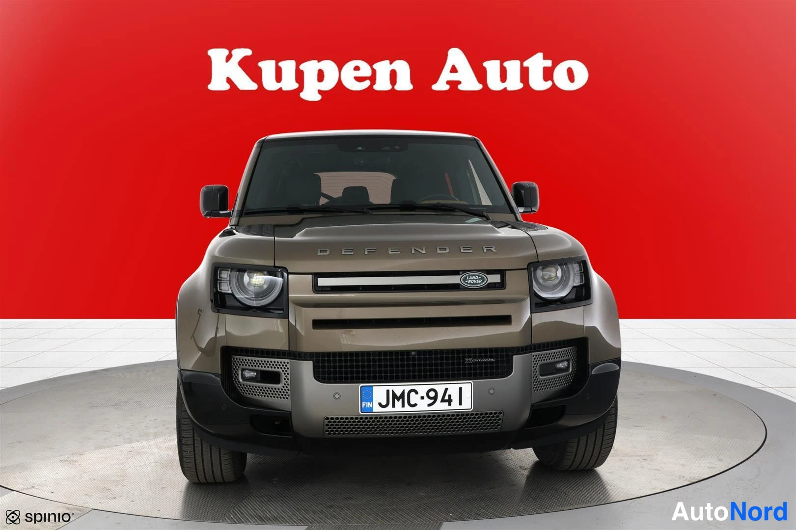 Edestä: Land Rover Defender suoraan edestä, DEFENDER-teksti konepellissä, rekisteritunnus.