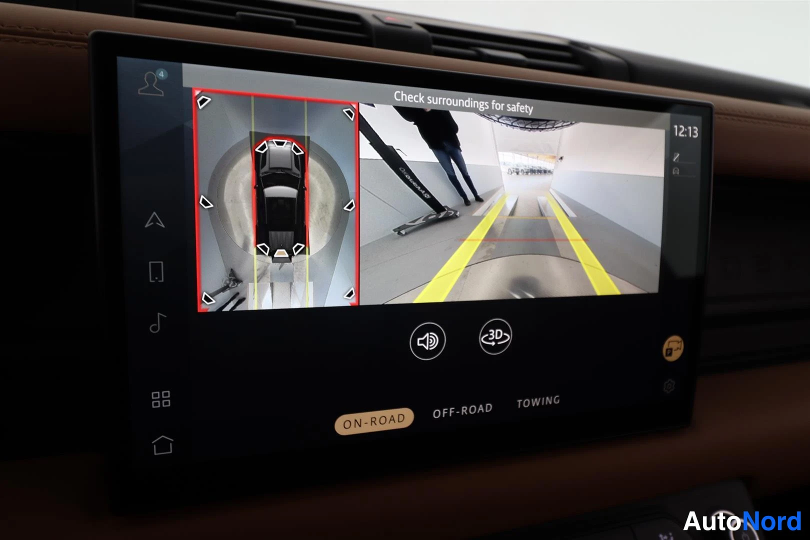 Yksityiskohta: Keskir konsolin näyttö näyttää ympäriviestikamerakuvan tekstillä 'Check surroundings for safety'