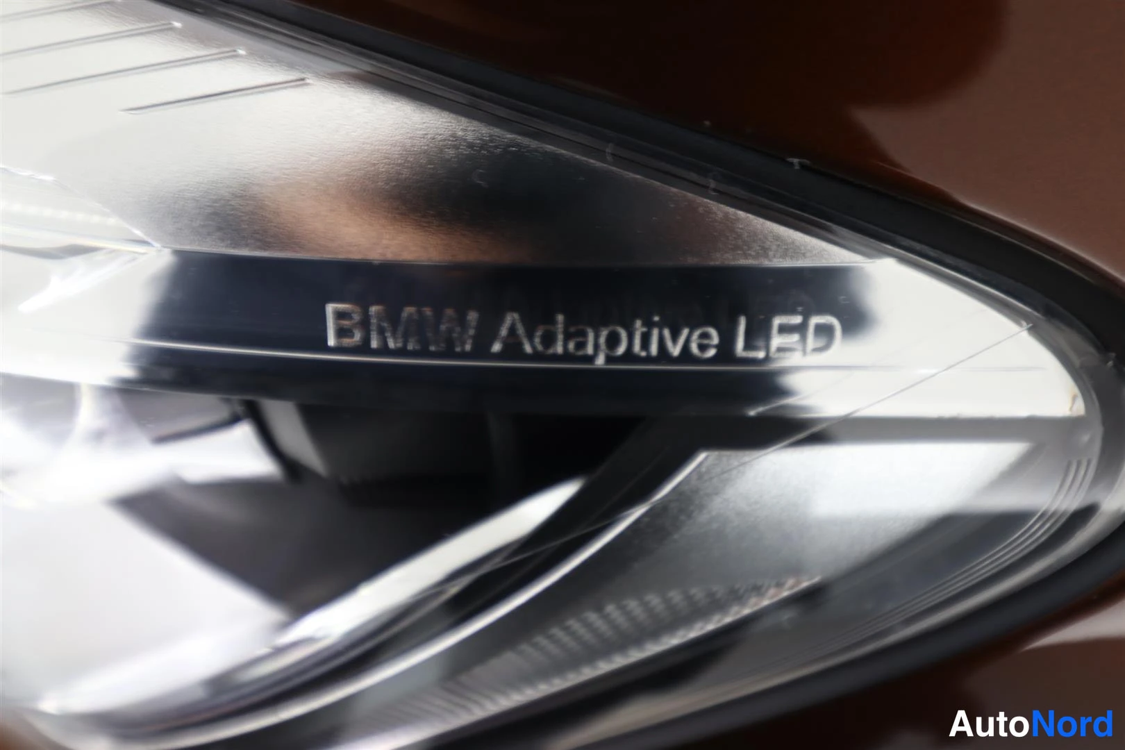 Yksityiskohta: BMW-etusuuntavalaisimen lähikuva, lasissa teksti 'BMW Adaptive LED'.
