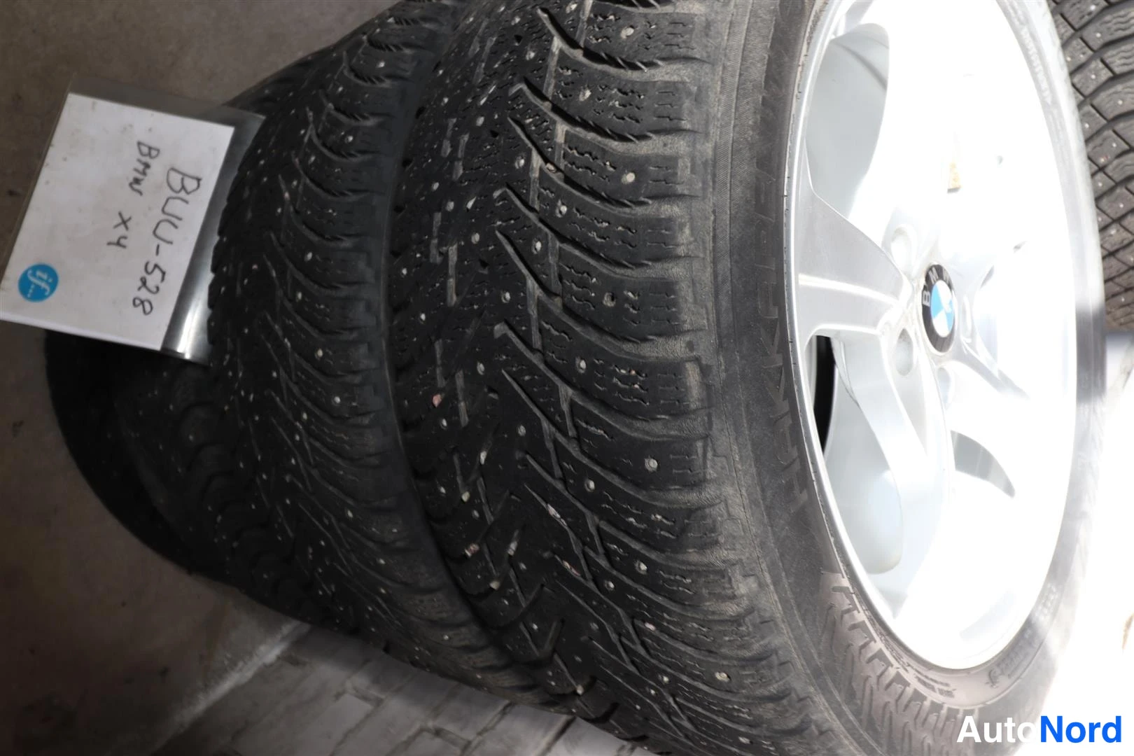 Yksityiskohta: Nastarenkaat kevytmetallivanteilla ja käsin kirjoitettu tarra, jonka lukee " Bmw X4".
