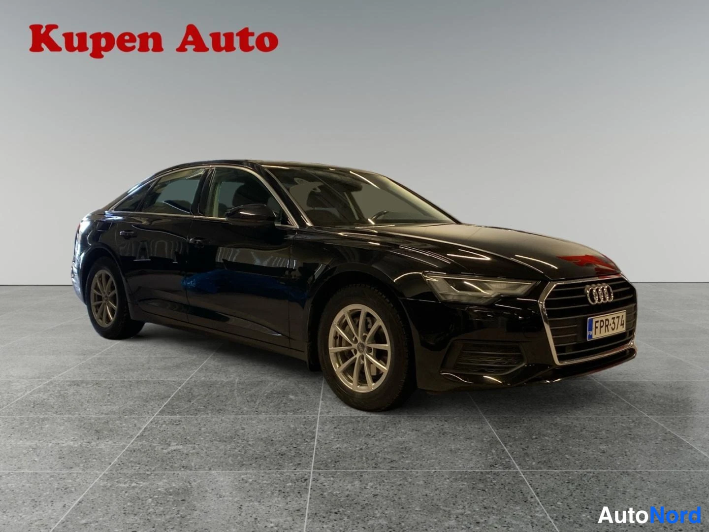 Etuviisto, nokka oikealle: Mustan Audi A6 -sedanin etukulmanäky oikealta, rekisterikilpi.