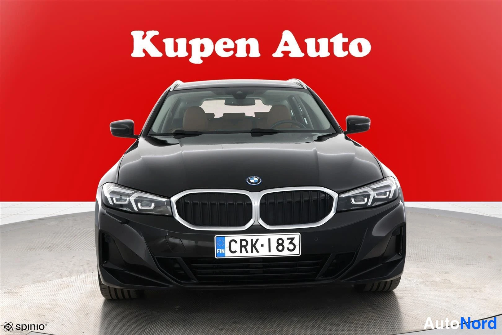 Edestä: Musta BMW 330 suoraan edestä valokuvattu, munuaissäleikkö ja LED-ajovalot punaisella taustalla.