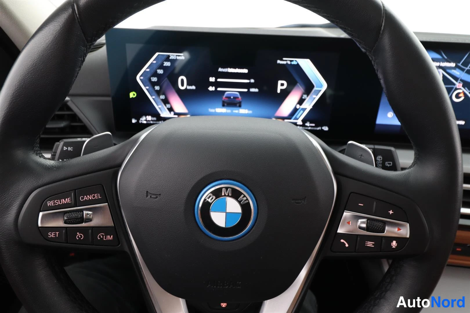 Sivulta: BMW-ohjauspyörä ja digitaalinen kojetaulu, vaihdetila P ja nopeus 0 km/h.