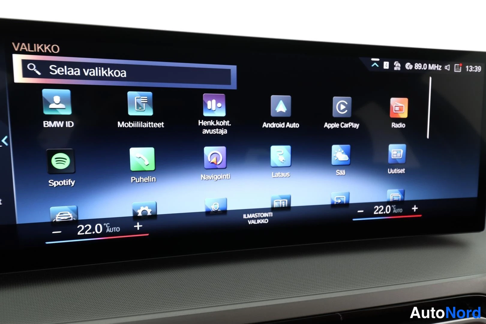 Yksityiskohta: Auton infotainment-näytön VALIKKO-näkymä, jossa mm. BMW ID, Mobiililaitteet, Android Auto, Apple CarPlay, Radio ja Spotify -sovellukset.