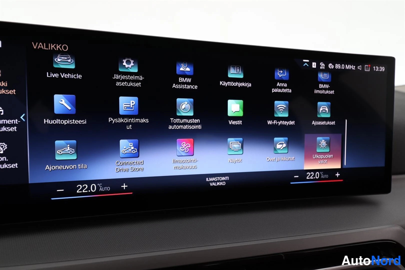 Yksityiskohta: Auton infotainment-näytön VALIKKO-näkymä, jossa mm. Live Vehicle, Järjestelmä-asetukset, BMW Assistance, Huoltopisteeseesi, Connected Drive Store ja Ajoneuvon t