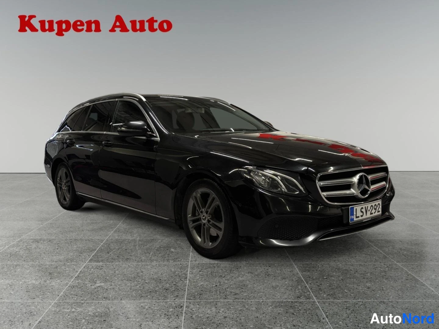 Etuviisto, nokka oikealle: Musta Mercedes-Benz E-sarjan farmari edestä oikealta kolmivartalokuvassa.