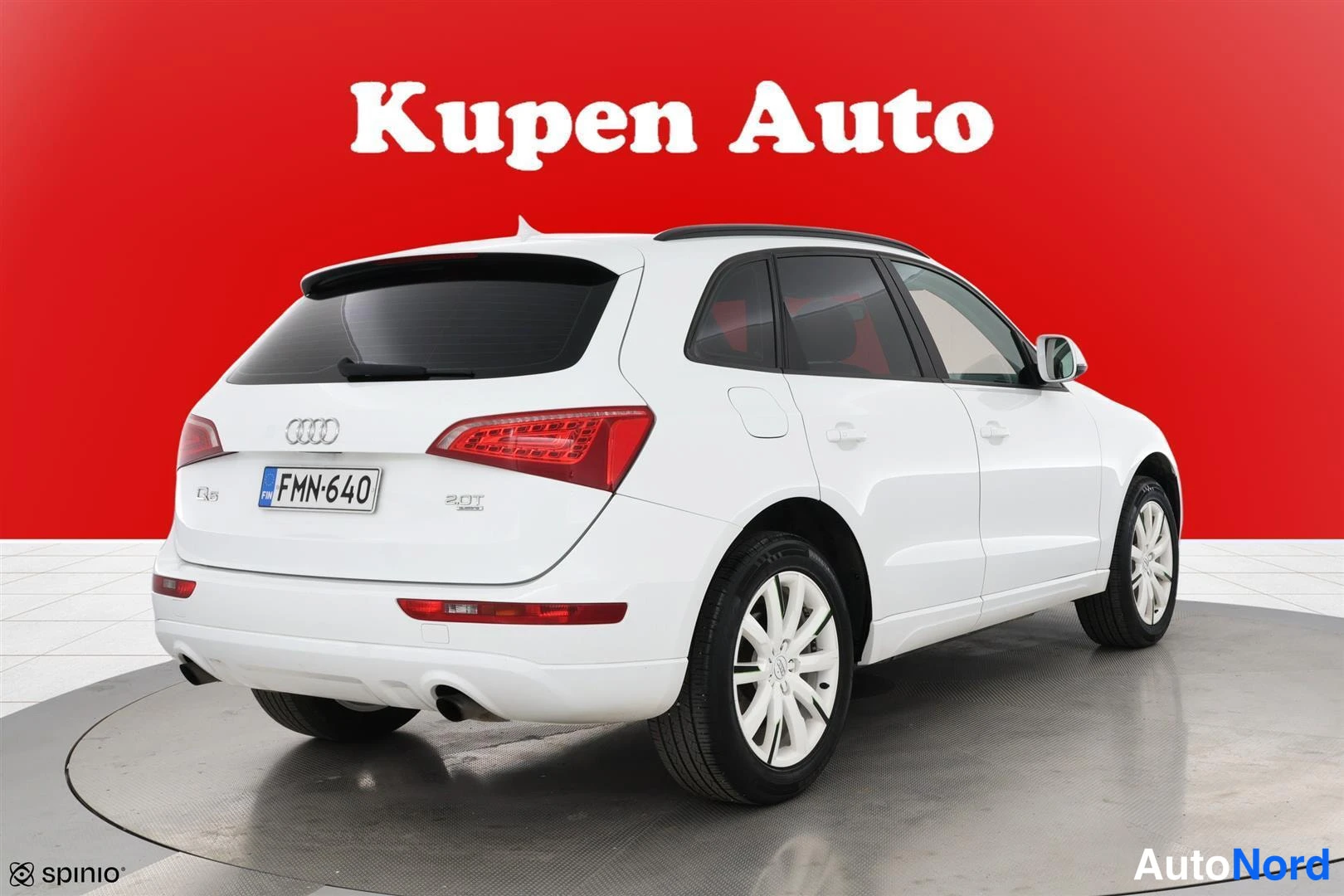 Takaviisto: Audi Q5 -farmarinta takaaviokuva: valkoinen koripaneeli, punaiset takavalot, -rekisterikilpi ja hopeat kevytmetallivanteet punaisella taustalla.