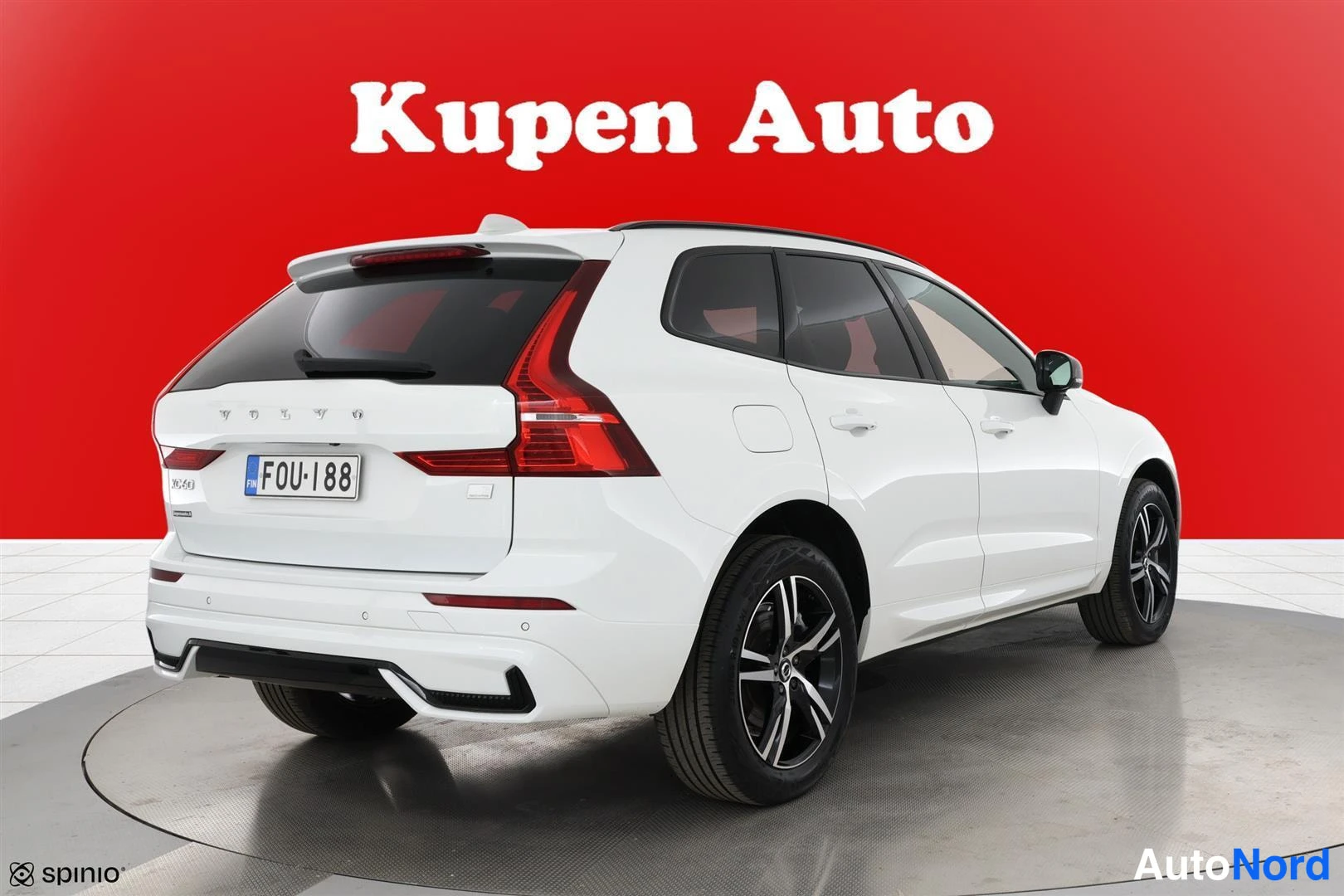 Takaviisto: Valkoinen Volvo XC60 takaa sivulta, mustat vanteet ja katolle kattokaiteet, punainen tausta.