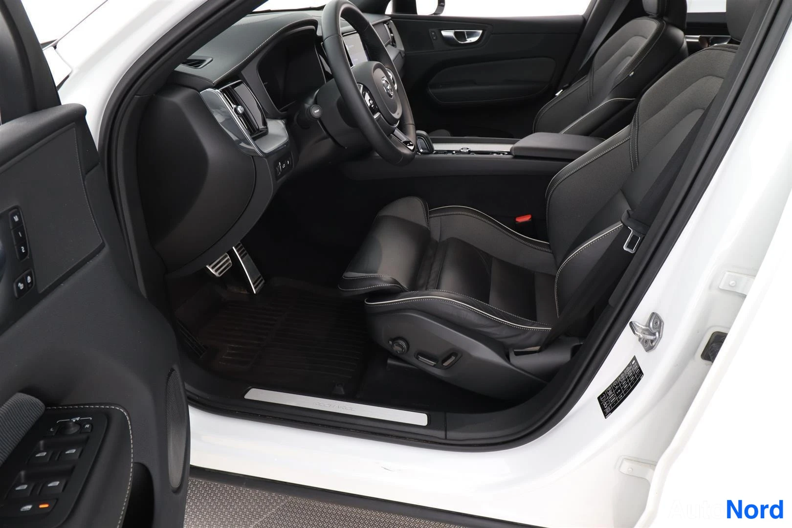 Etuistuimet: Volvo XC60:n etusohva mustat penkit, etummat istuimet ja ohjauspyörä näkyvät avatusta ovesta.