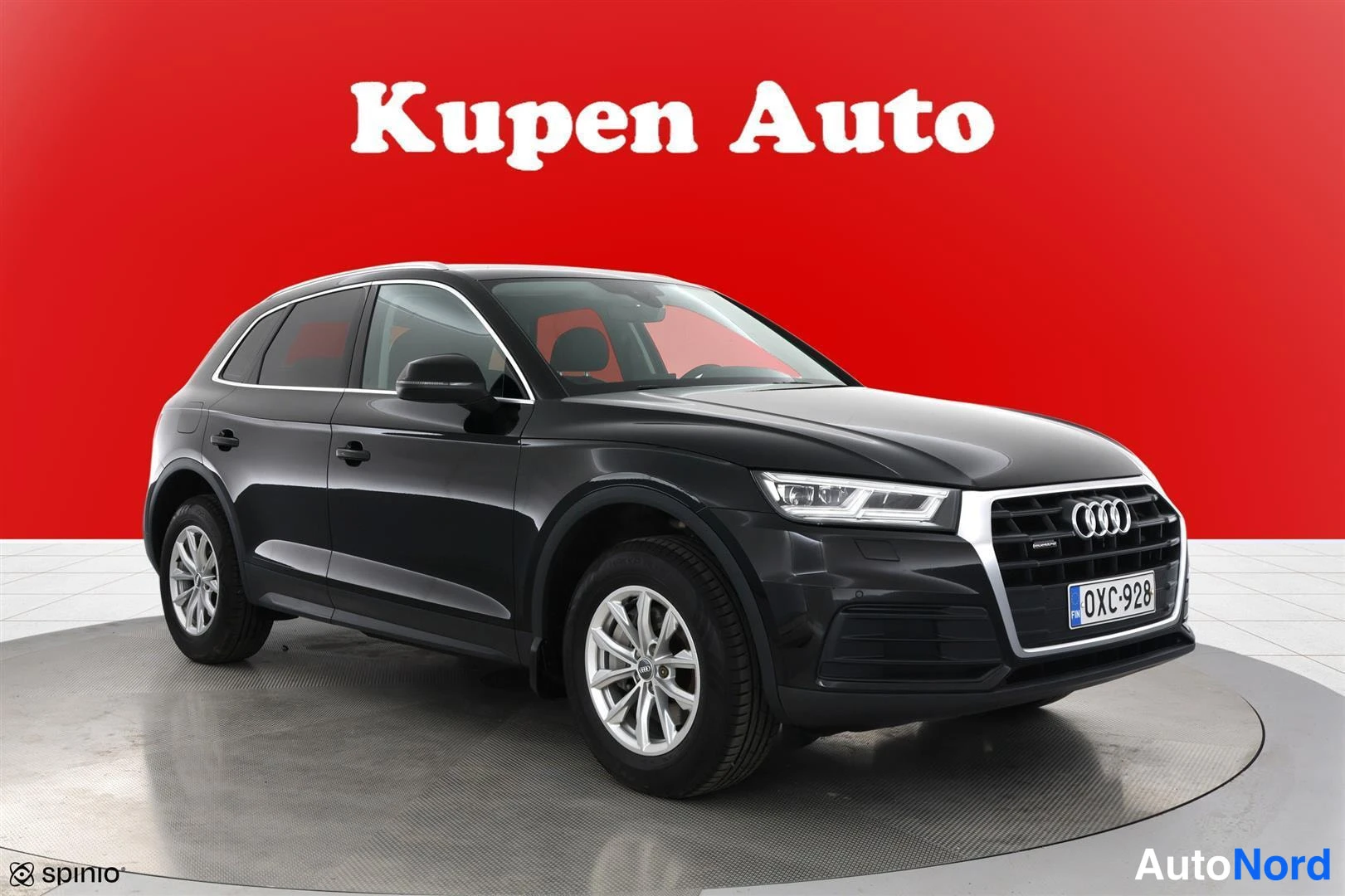 Etuviisto, nokka oikealle: Musta Audi Q5 etuviistosta oikealta, punainen tausta ja Kupen Auto -teksti.