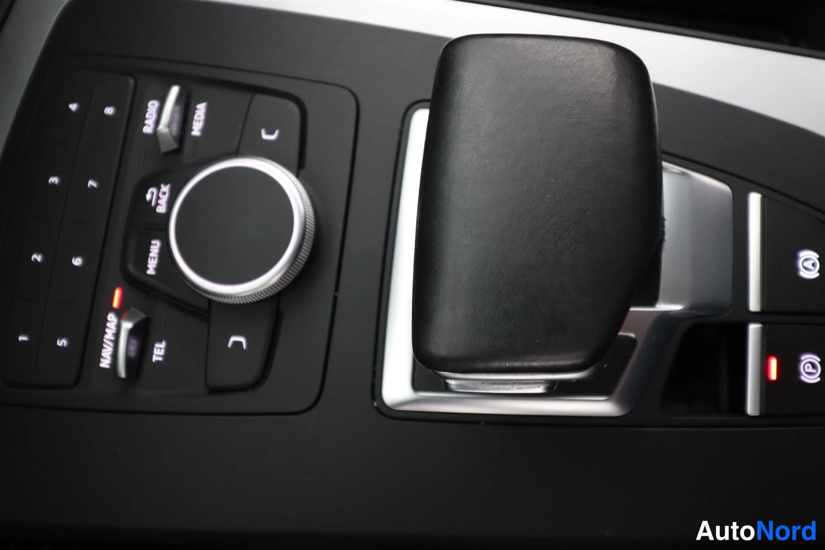 Yksityiskohta: Audi-auton keskikonsolin MMI-käyttöpaneeli ja automaattivaihteen valitsinvipu.
