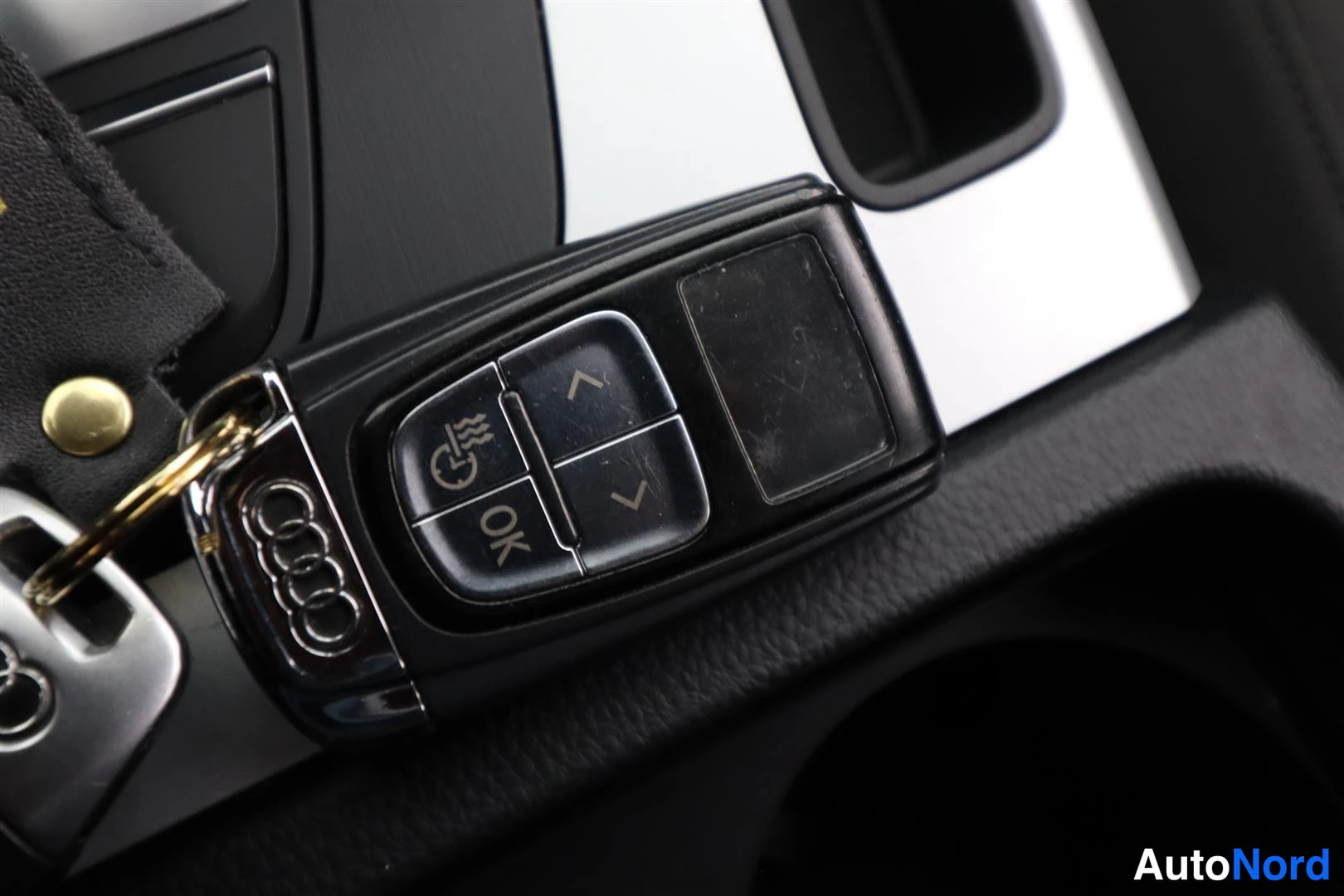 Yksityiskohta: Audi-avain, jossa MMI-touchpaneeli ja OK-näppäin, konsolilla levytakkana.