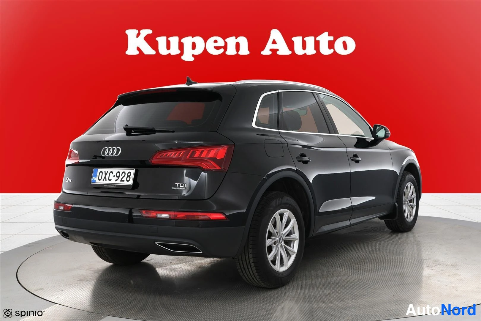 Takaviisto: Musta Audi Q5 takaviistosta oikealta, koko auto näkyvissä punaisella taustalla.