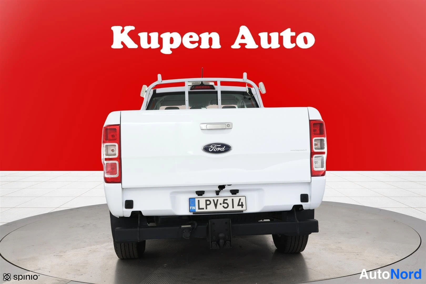Takaa: Auton takanäkyvys: valkoinen lavallisella avolavalla varustettu pickup, takaluukussa Ford-merkki, rekisterikilpi ja harja sekä ilo- ja jarruvalot punaisina.