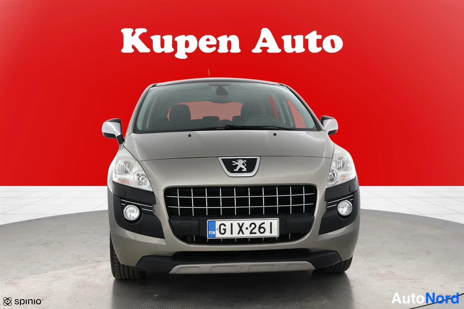 Edestä: Peugeot-auton suora etunäkymä; hopeanharmaa kori, rekisterikilpi, punainen tausta.