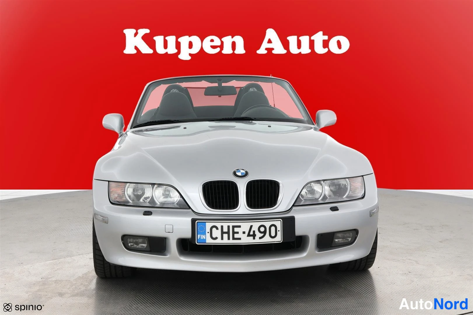 Edestä: Hopeanvärinen BMW Z3 Roadster suoraan edestä kuvattuna, avokatto auki, punainen tausta.