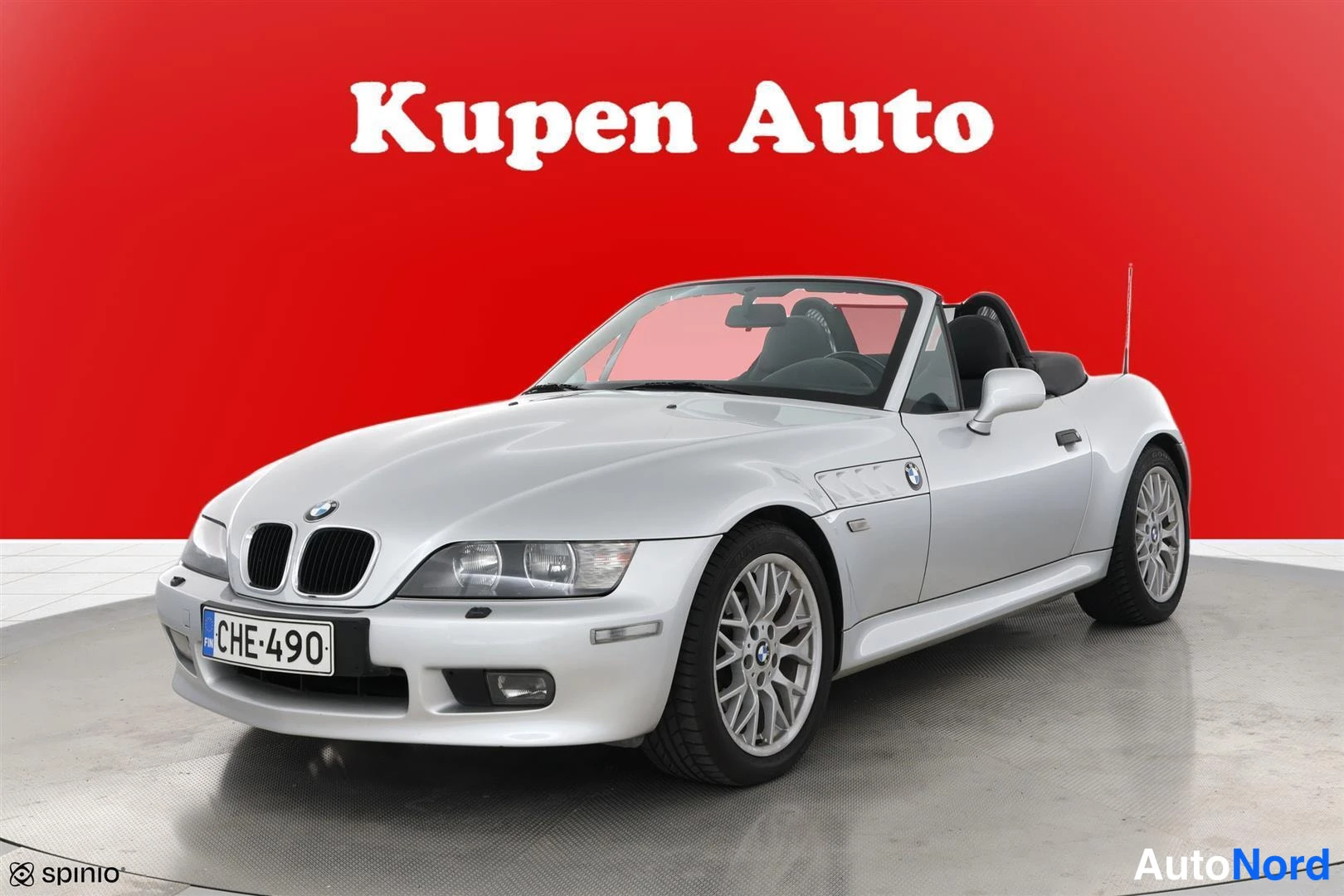 Etuviisto, nokka vasemmalle: Hopeanvärinen BMW Z3 Roadster edestä oikealta kolmivelokulmassa, avokatto auki, punainen tausta.