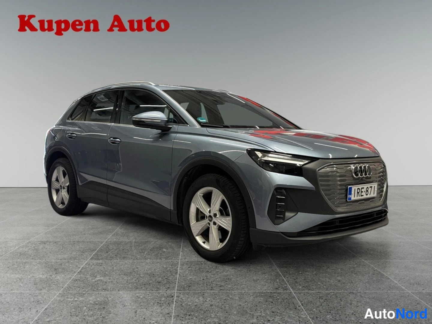 Etuviisto, nokka oikealle: Sinertävänharmaa Audi Q4 e-tron edestä oikealta kuvattuna, kylki ja keulagrailli näkyvissä, rekisterikilpi.