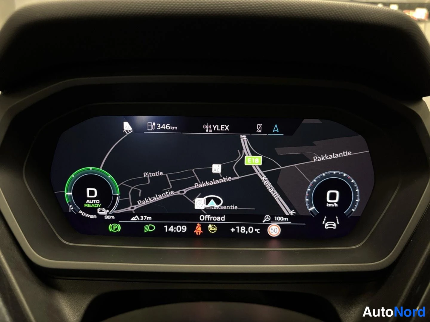Muu: Ajovalot päällä, 98 %:n lataus, D-valinta, navigointi Offroad-näkymässä, ulkolämpötila +18,0 °C ja nopeusrajoitus 50 km/h näkyvät digitaalisessa mittaristossa.