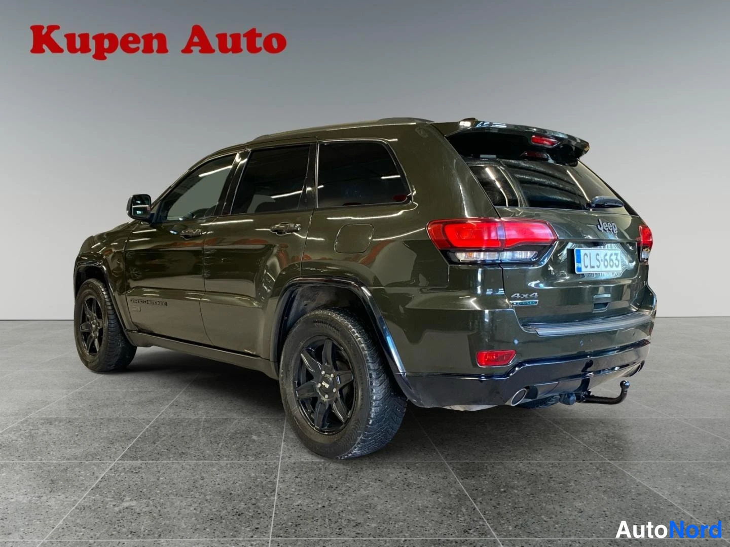 Takaviisto: Tummanvihreä Jeep Grand Cherokee takaa vasemmalta kuvattuna, rekisterikilpi ja mustat vanteet.
