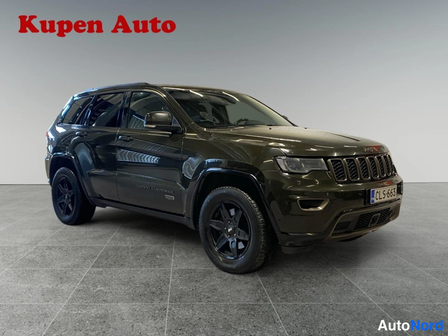 Etuviisto, nokka oikealle: Tummanvihreä Jeep Grand Cherokee kolmivartalokuvassa edestä oikealta, mustat vanteet ja rekisterikilpi.