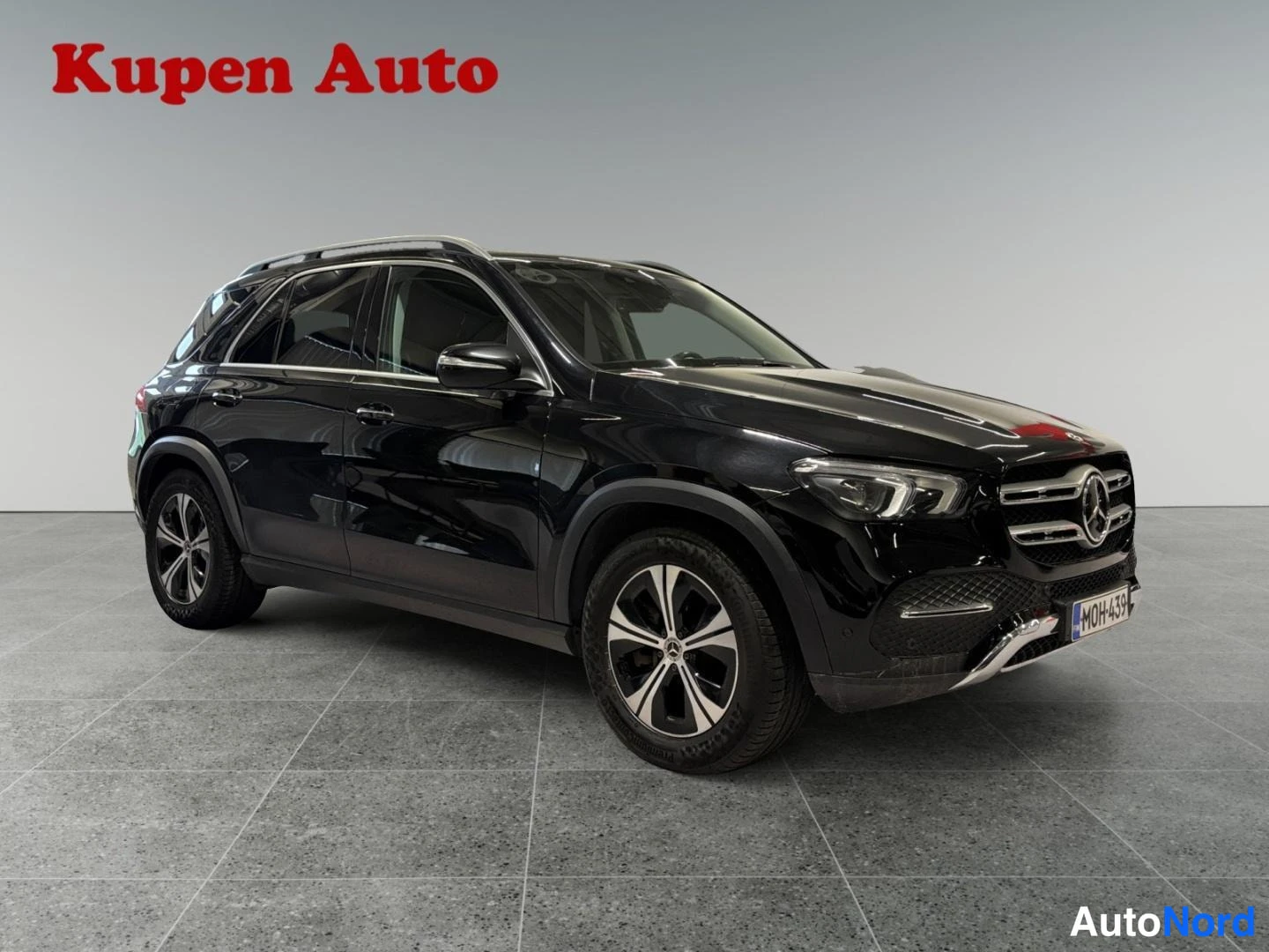 Etuviisto, nokka oikealle: Musta Mercedes-Benz GLE -maasturi kuvattu kolmesta neljäsosasta edestä oikealta, etusäleikkö ja oikea kylki näkyvät studiohallissa.