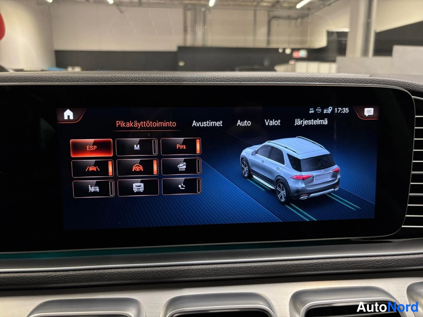Yksityiskohta: Multimediajenäytön Pikakäyttötoiminto-valikko avustinten kuvakkeineen ja autongrafiikalla