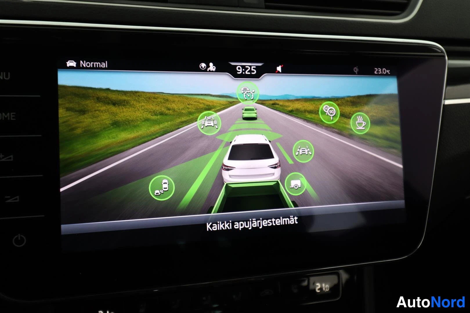 Muu: Auton infotainment-näyttö esittää mallikuvaa autosta tiellä, ympärillä vihreällä korostettuja kuljettajaa auttavia järjestelmiä; alatekstinä 'Kaikki apujärjeste