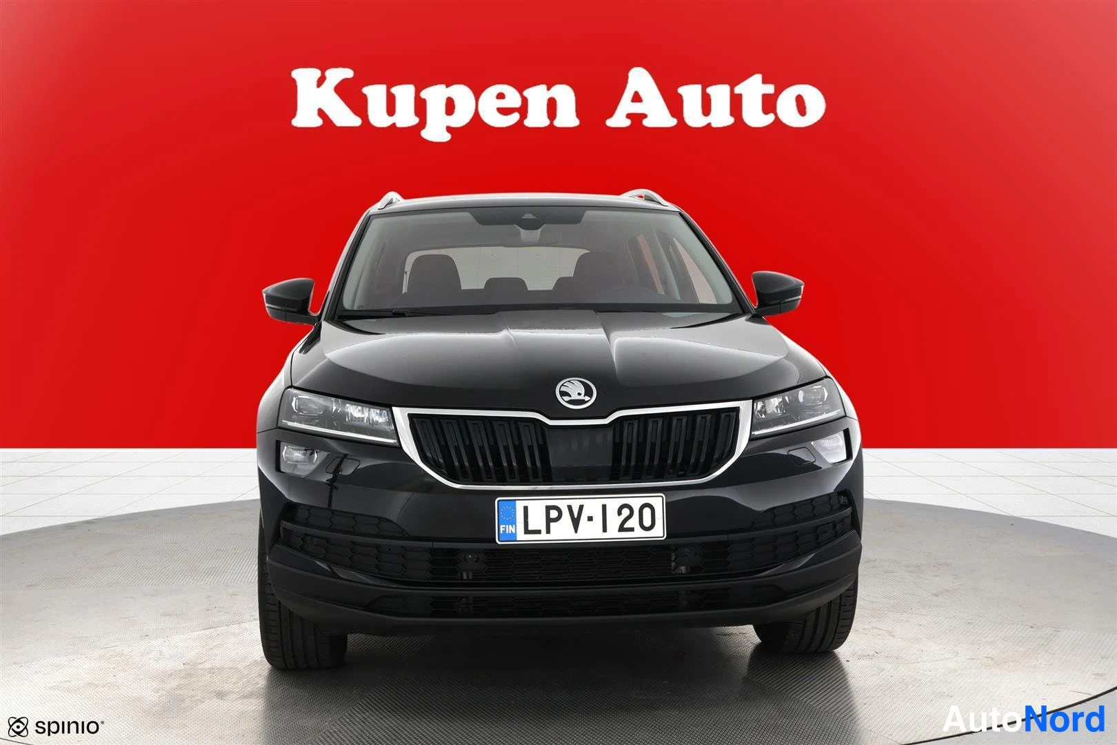 Edestä: Mustan Skoda Karoqin etukuva suoraan edestä, rekisterikilpi punaista taustaa vasten.