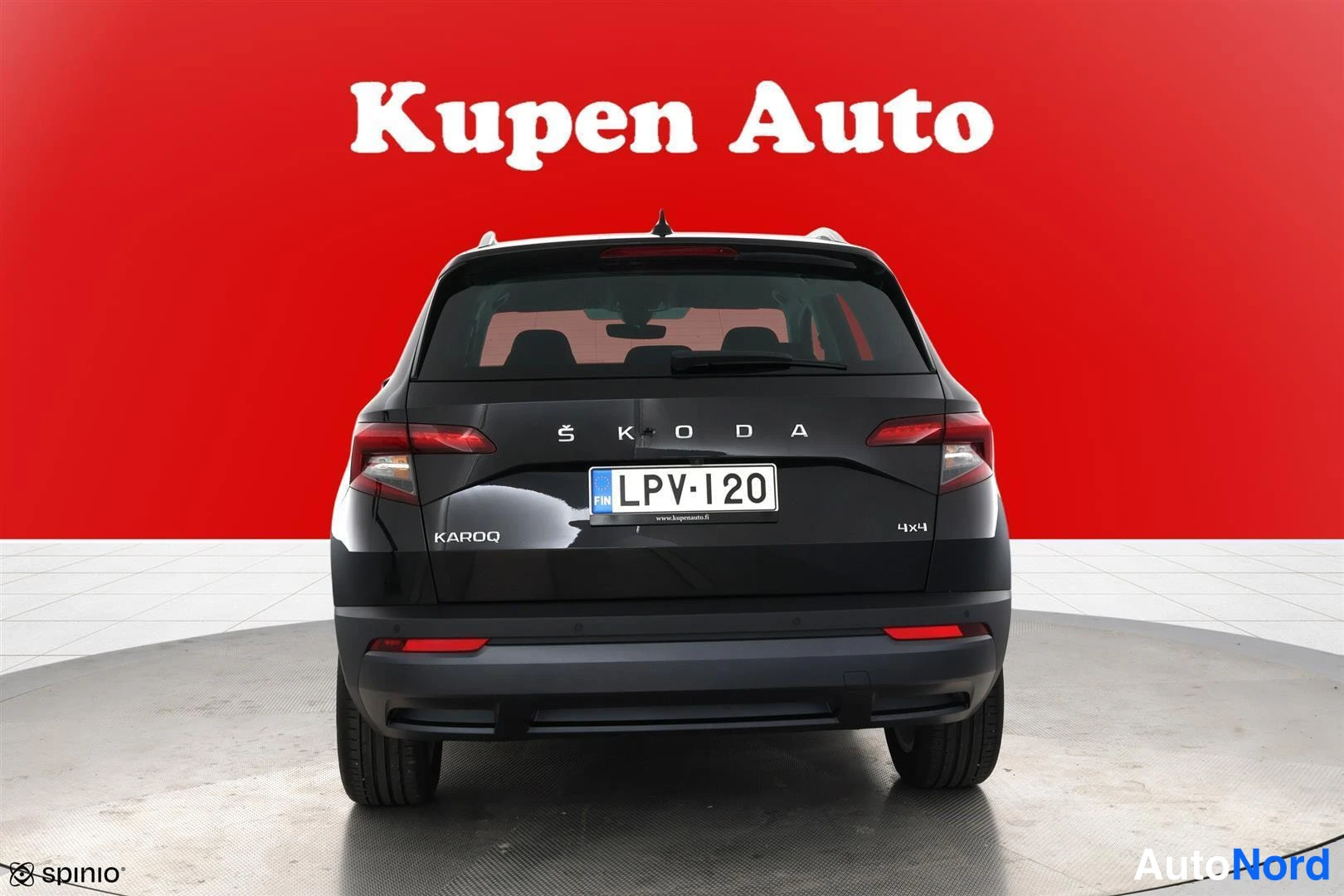 Takaa: Auton takanäkymä punaisella taustalla, rekisterikilpi, ŠKODA- ja KAROQ-merkit sekä 4x4-merkintä takaluukussa.