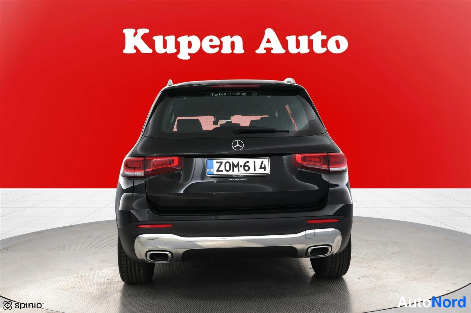 Takaa: Musta Mercedes-Benz -maastoauto suoraan takaa, rekisterikilpi, punainen tausta.