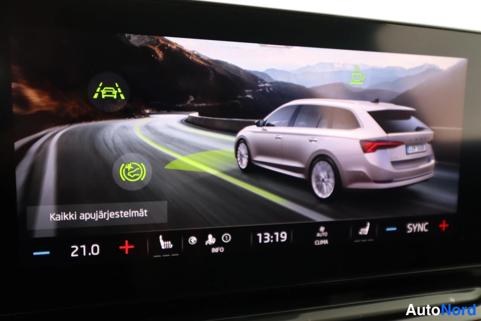 Yksityiskohta: Infotainment-näyttö 'Kaikki apujärjestelmät' -näkymässä, lämpötila 21.0 astetta.