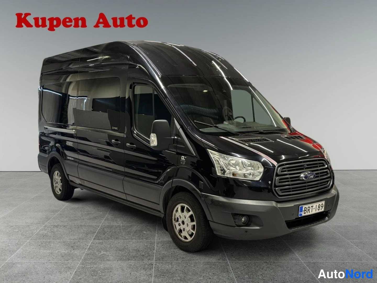 Etuviisto, nokka oikealle: Musta Ford Transit -pakettiauto etuviistosta oikealta, rekisteritunnus.