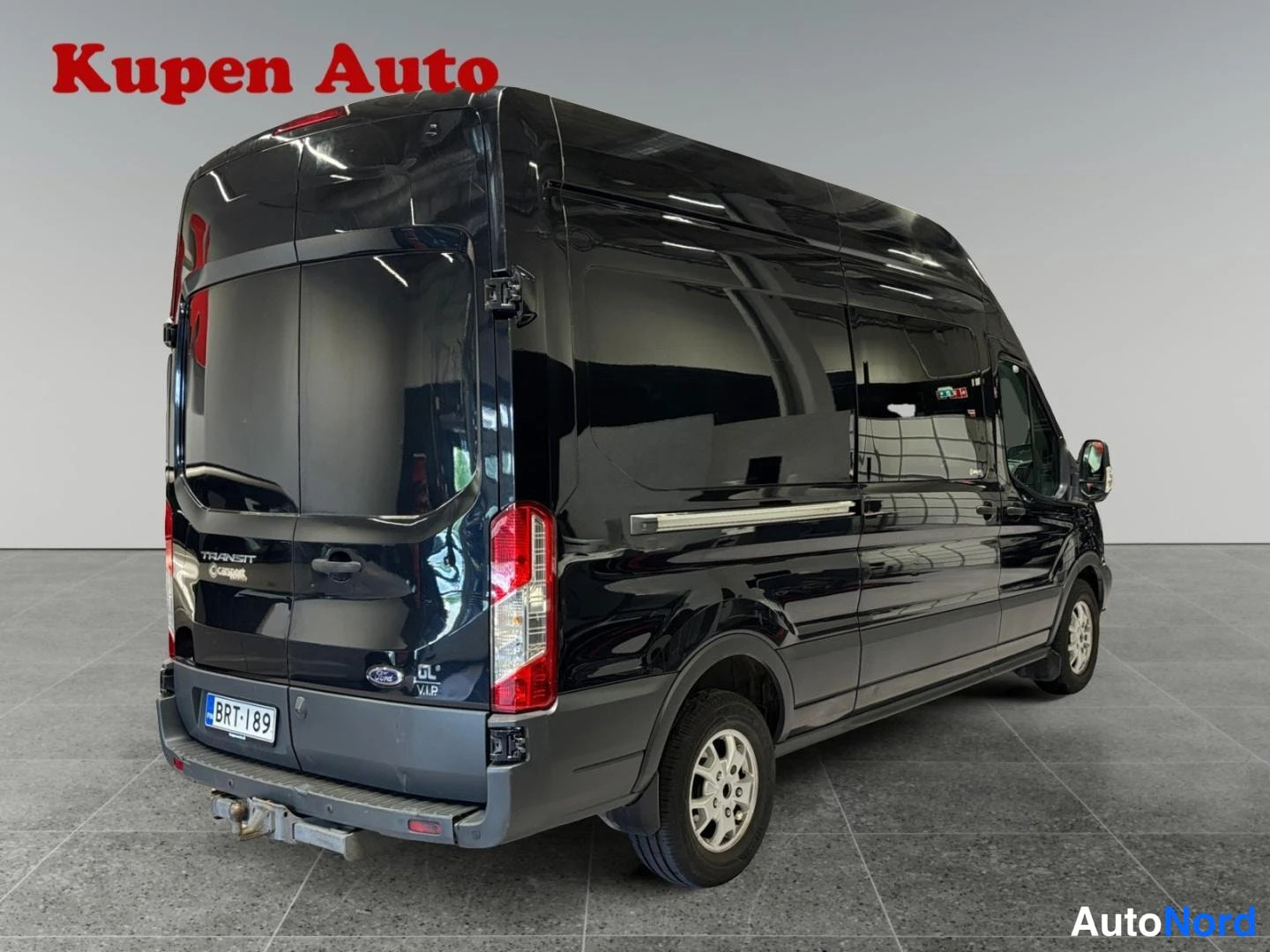 Takaviisto: Mustan Ford Transit -pakettiauton takaosa ja vasen kylki, takaluukussa TRANSIT-teksti ja rekisteritunnus.